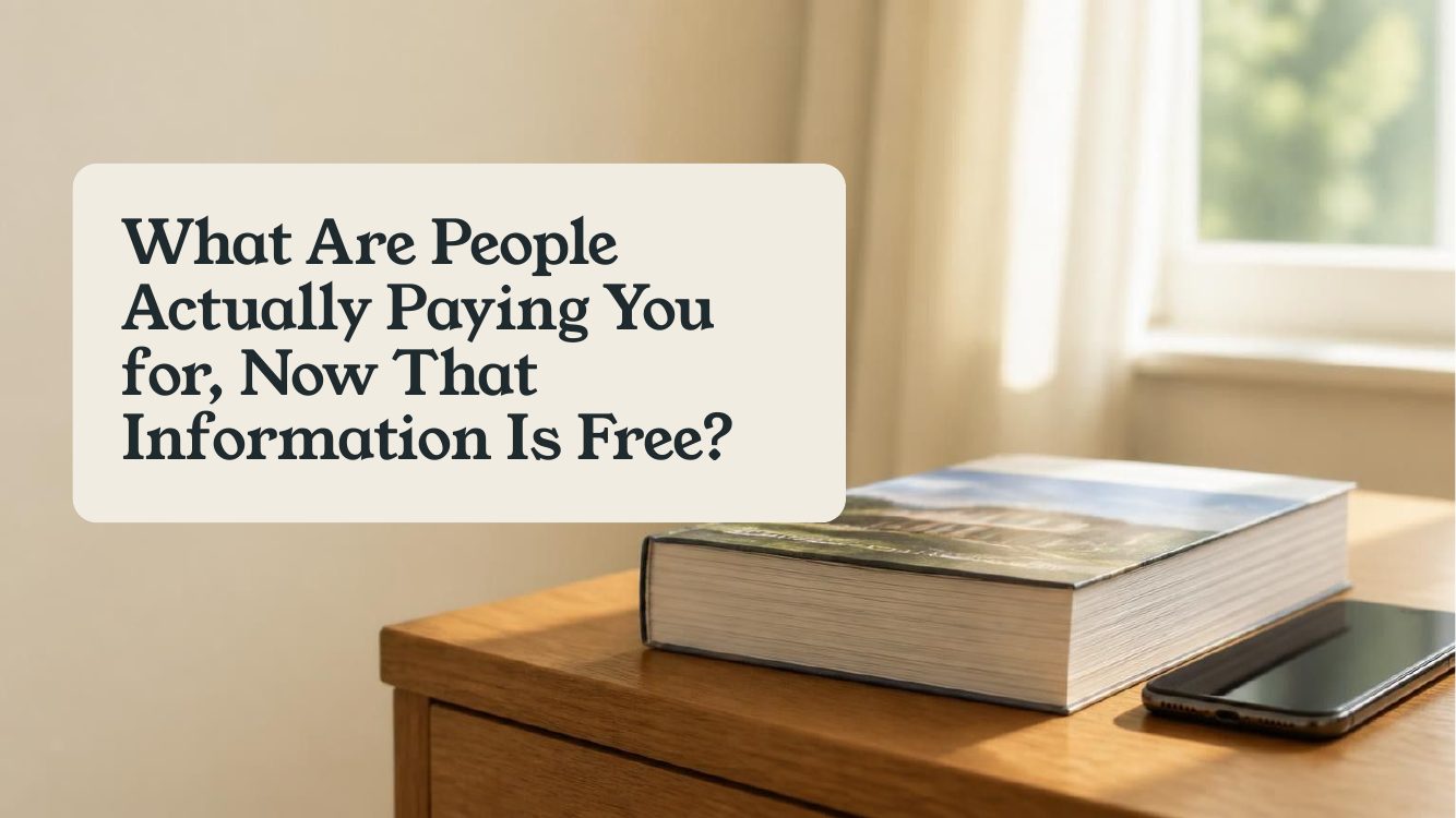 What Are People Actually Paying You for, Now That Information Is Free? A book and a phone on a wooden desk in morning light